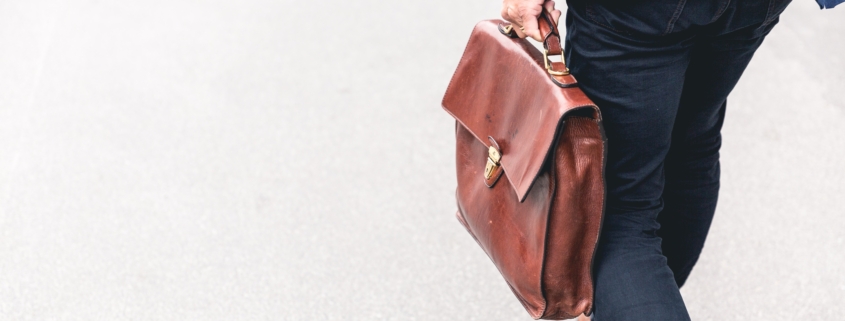 Person walking holding brown briefcase