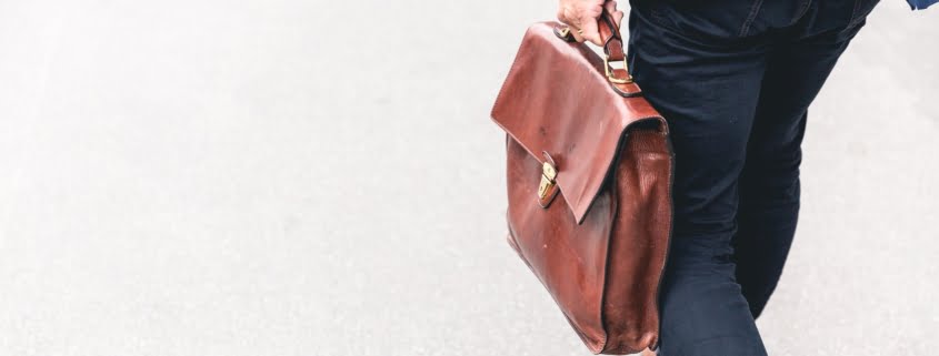 Person walking holding brown briefcase